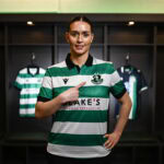Shamrock Rovers female player in team jersey at locker room.
